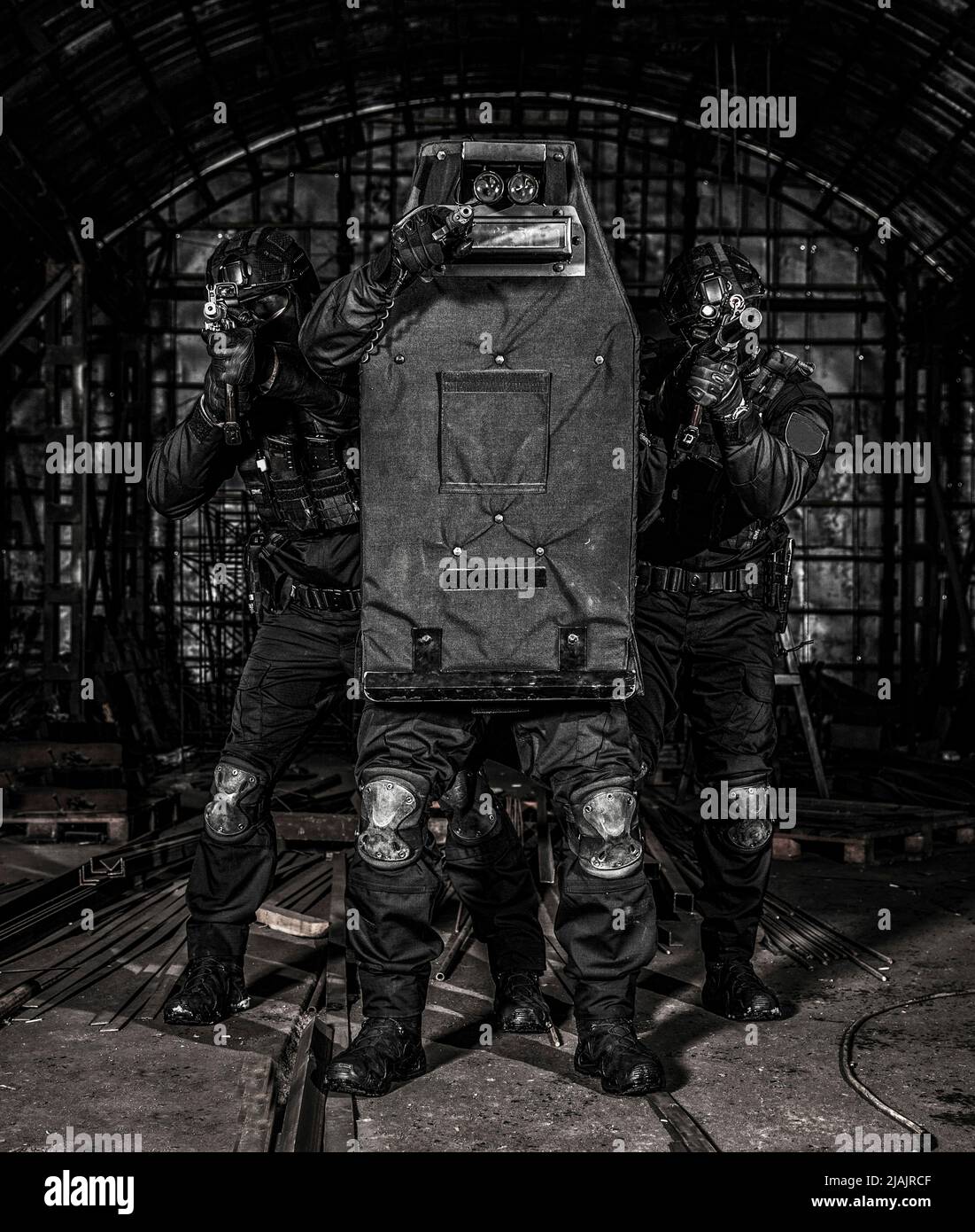 SWAT-Teammitglieder verstecken sich hinter ballistischem Schild und zielen auf ihre Waffen. Stockfoto