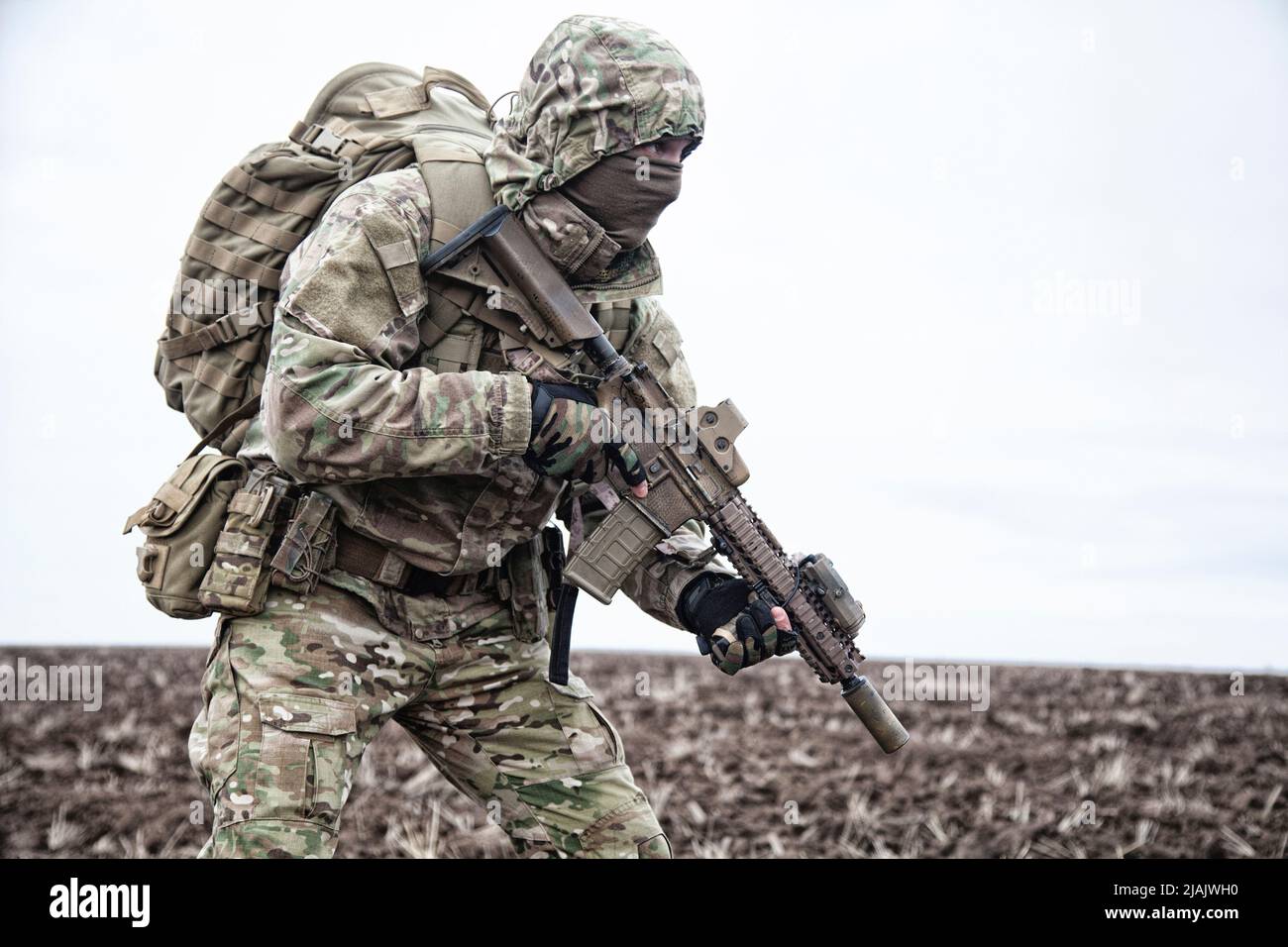 Militär Söldner tragen Kapuze Camo Jacke und Rucksack, zu Fuß durch schlammiges Gelände. Stockfoto