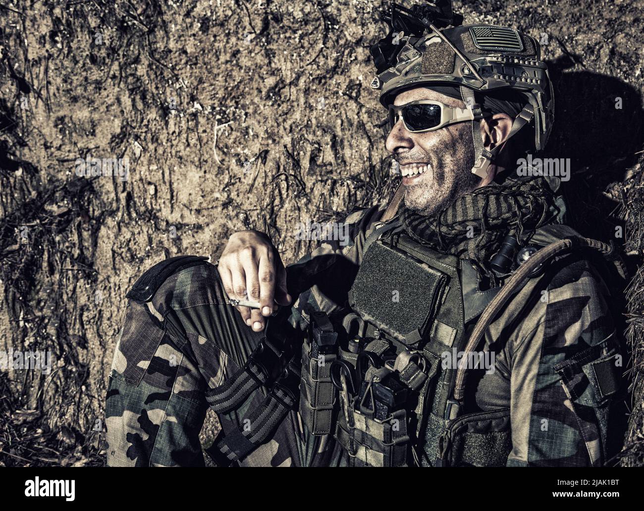 Ein Soldat, der nachts in den Schützengräben ruht und lächelt, während er eine Zigarette raucht. Stockfoto