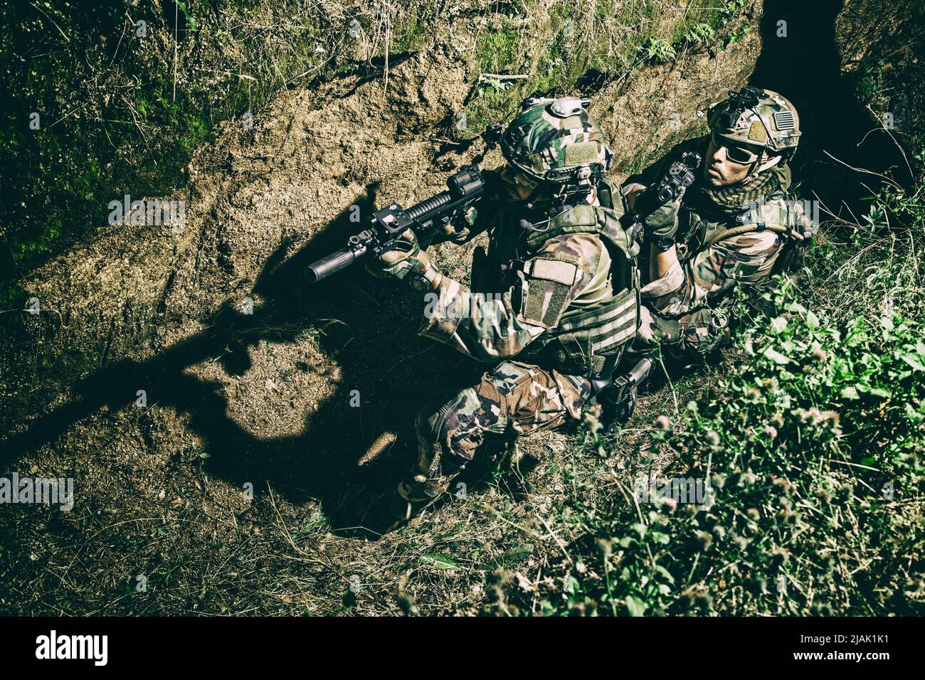 Soldaten decken sich gegenseitig ab, während sie sich nachts in einem Graben auf dem Schlachtfeld bewegen. Stockfoto