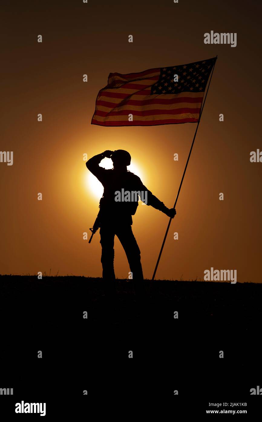 Silhouette eines US-Soldaten, der während des Sonnenuntergangs die Nationalflagge schwenkt. Stockfoto