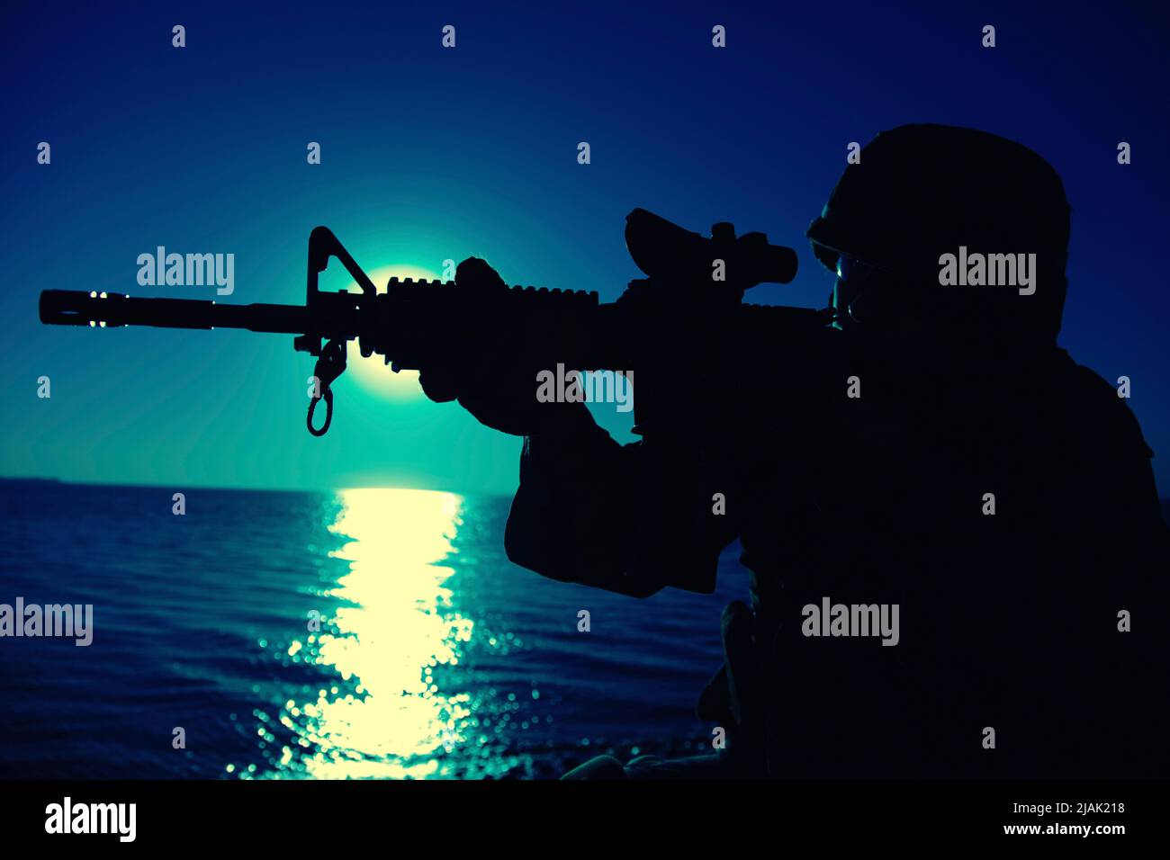 Silhouette eines Soldaten mit Sturmgewehr und Kollimatorblick bei Nacht. Stockfoto