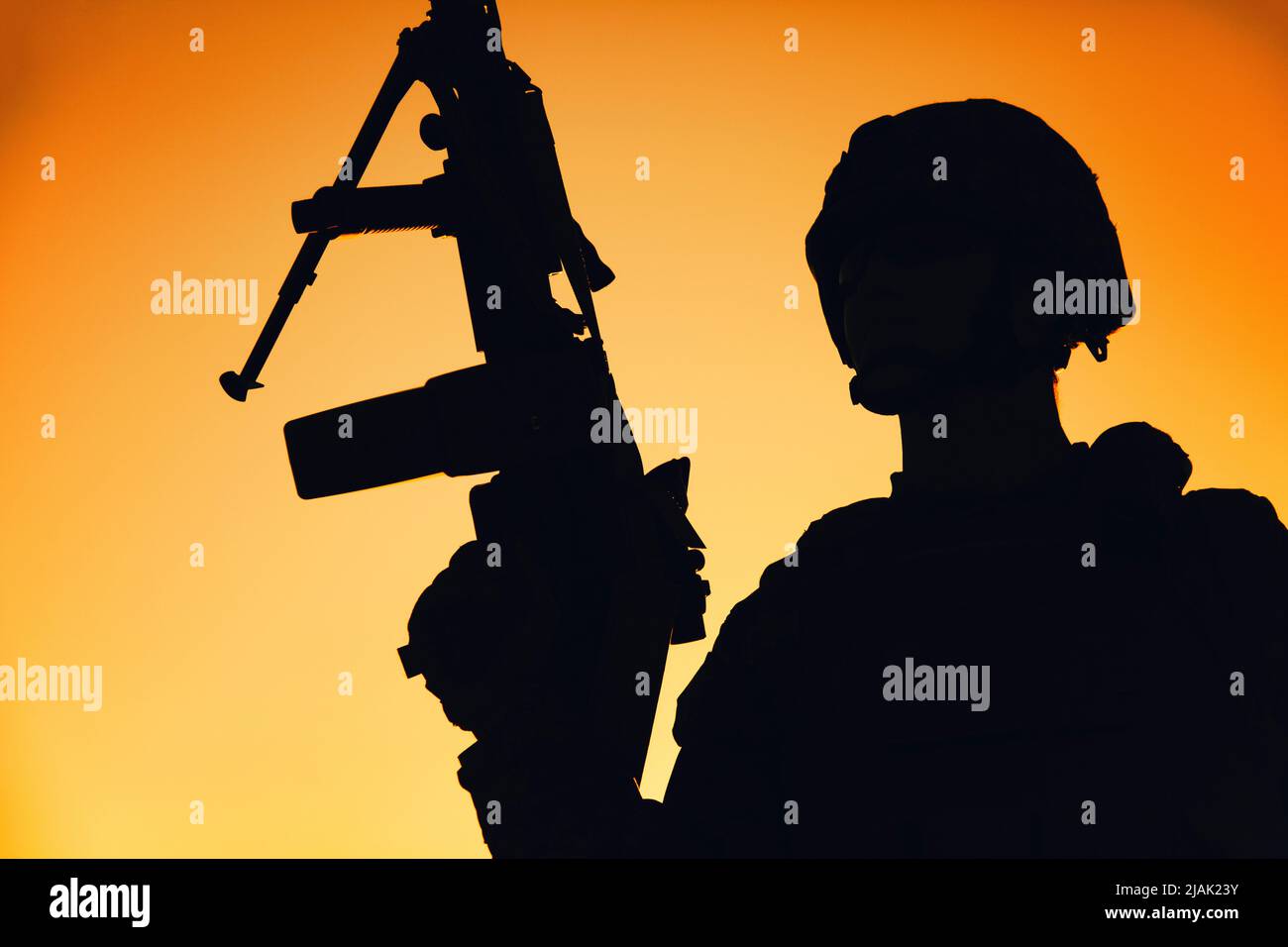 Silhouette eines Soldaten, der im Morgengrauen Waffe hält. Stockfoto