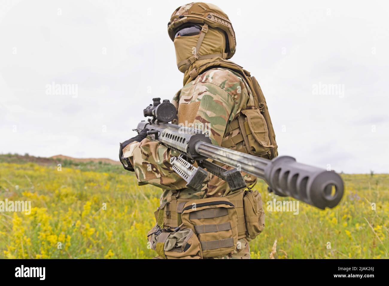 Soldat der Spezialeinheiten, der auf einem grünen Feld mit einem Scharfschützengewehr steht. Stockfoto