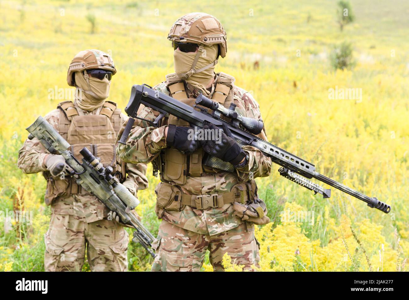 Zwei bewaffnete Soldaten mit Gewehren auf einem blühenden Feld. Stockfoto