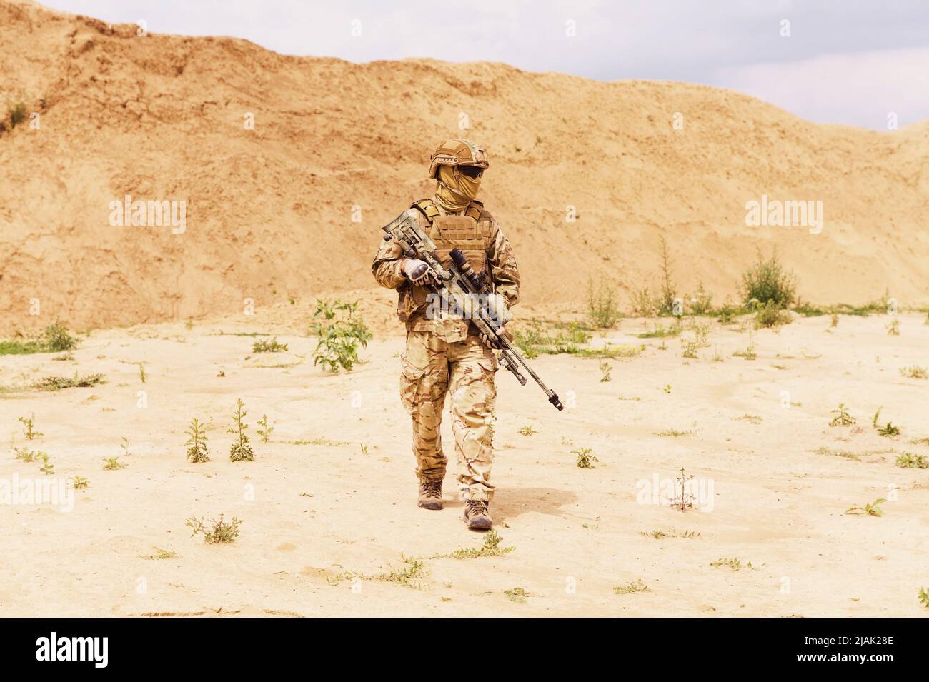 Ausgerüsteter Soldat der Spezialeinheiten, der durch die Wüste läuft. Stockfoto