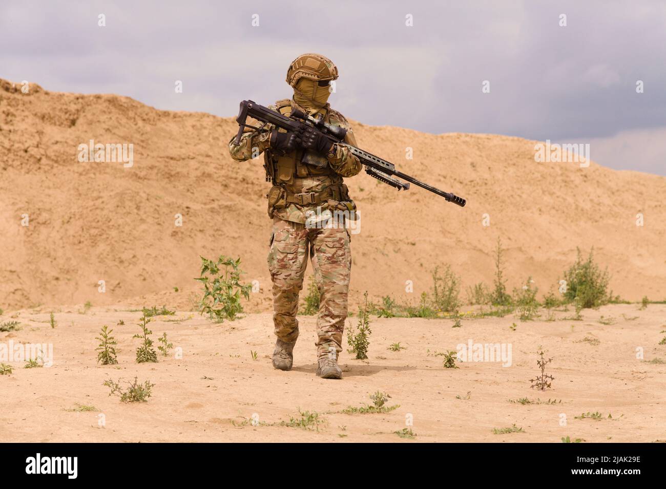 Ausgerüsteter und bewaffneter Spezialeinsatzsoldat mit Gewehr in der Wüste während einer Militäroperation. Stockfoto