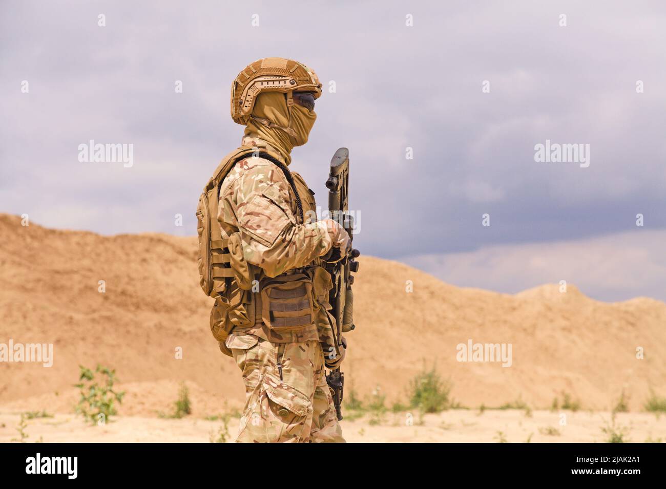 Bewaffneter Soldat in Tarnung mit Gewehr in der Wüste. Stockfoto