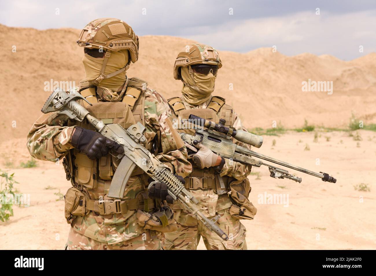 Zwei bewaffnete und bewaffnete Soldaten der Spezialeinheiten mit Gewehren in der Wüste. Stockfoto