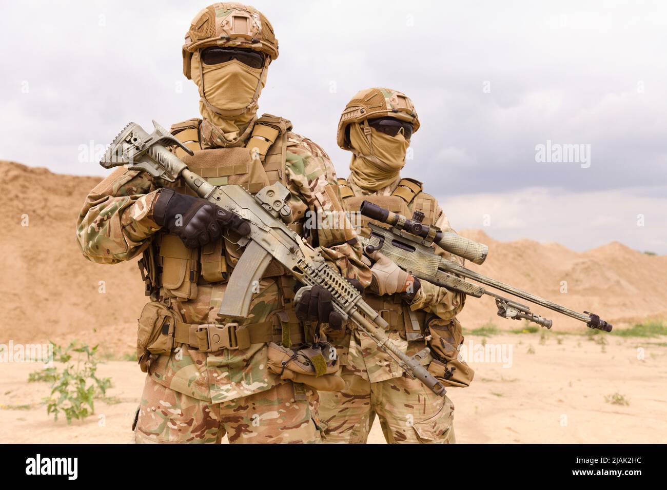 Zwei bewaffnete und bewaffnete Soldaten der Spezialeinheiten stehen in der Wüste. Stockfoto