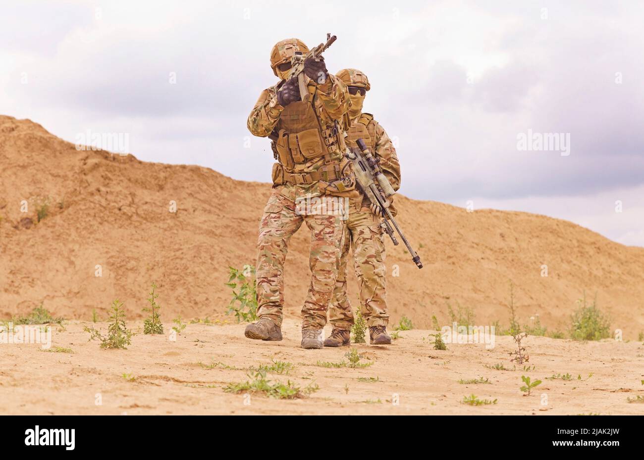 Bewaffnete und bewaffnete Spezialeinheiten Soldaten schießen Gewehre in der Wüste. Stockfoto