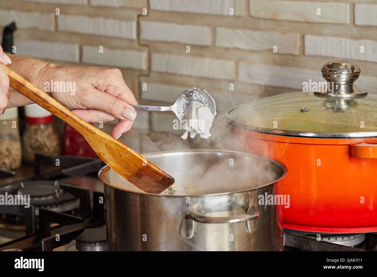 Frische Creme wird nach Rezept aus dem Internet auf dem Gasherd in die Pfanne geworfen. Dampftopf Stockfoto