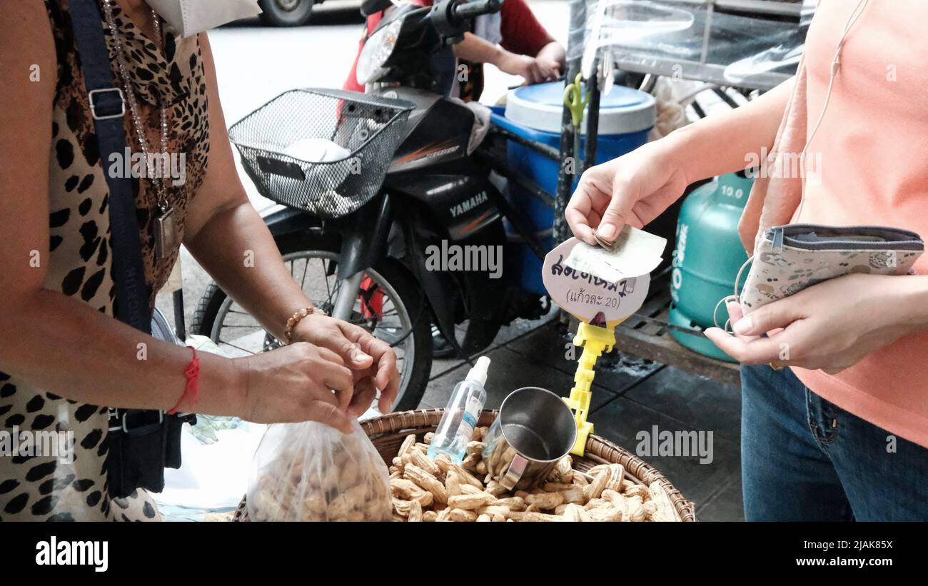 Geldwechsel Hände Straßenhändler Verkauf Erdnüsse Bargeld und tragen Sukhumvit Road Nana Gegend Bangkok Thailand Stockfoto