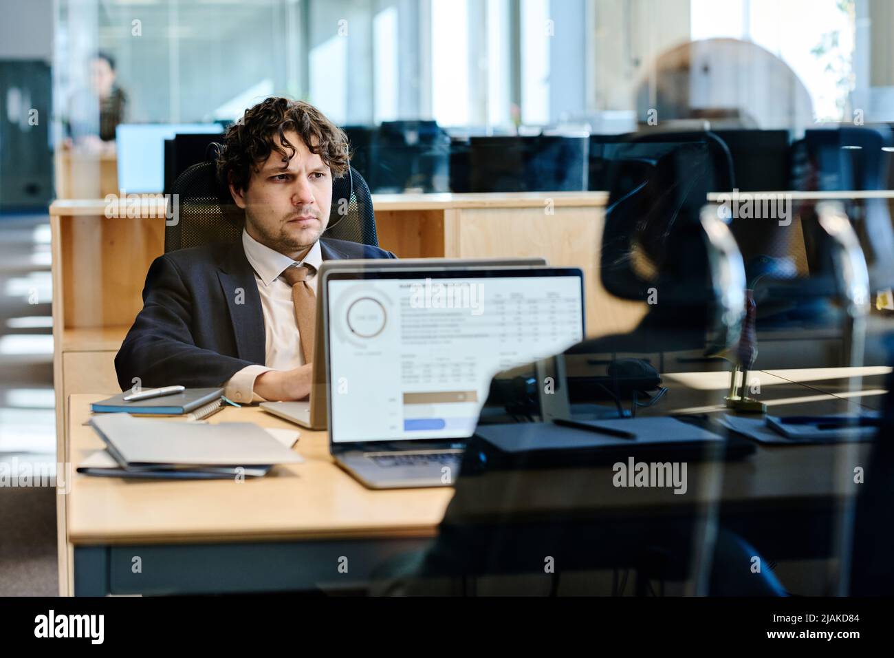 Geschäftsleute, die an einem Tisch hinter einer Glaswand im Büro an einem Laptop arbeiten Stockfoto