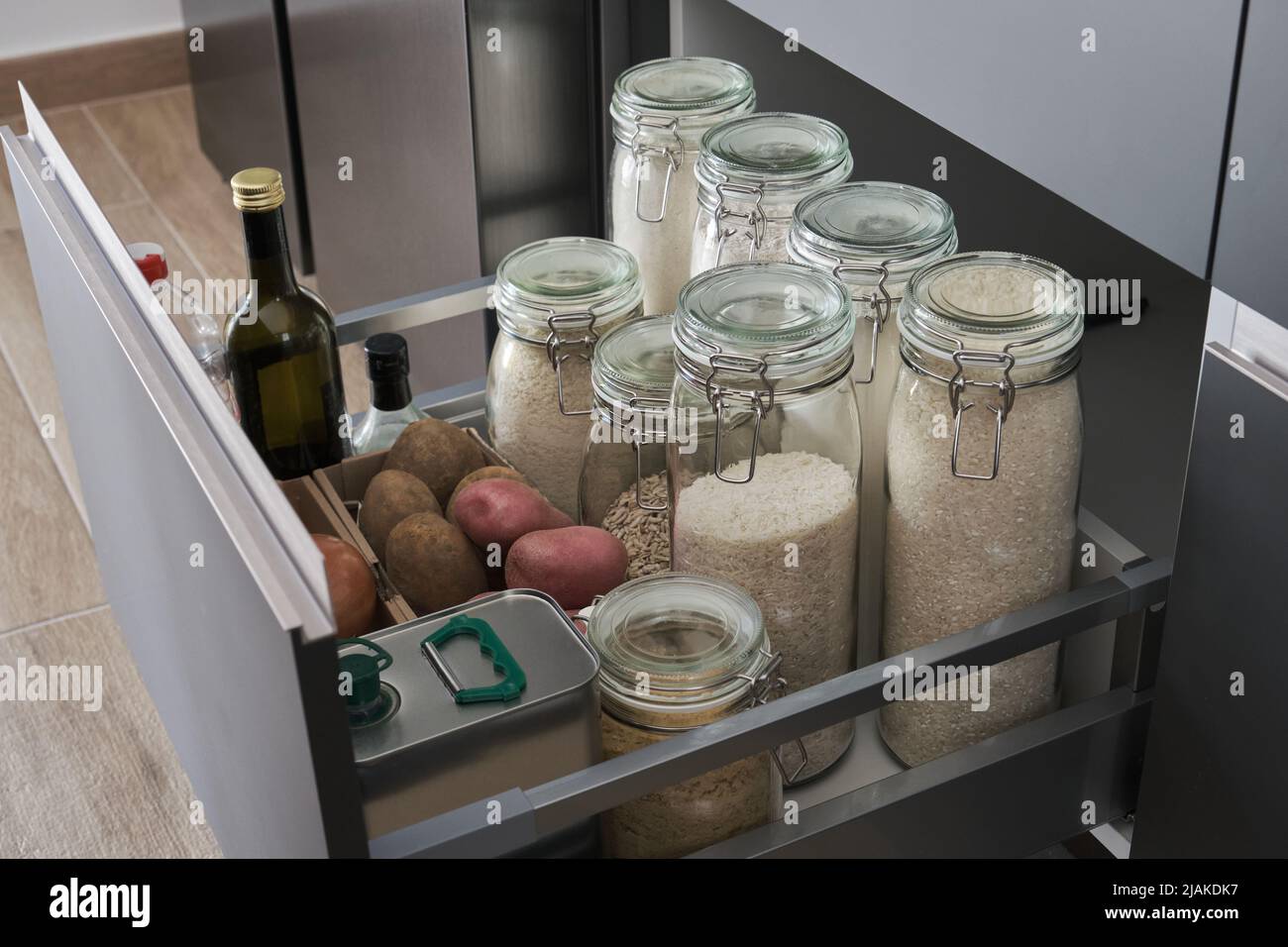 Verschiedene Mehle, Ries, Kartoffeln, Zwiebeln, Öl, Essig in der Küchenschublade. Stockfoto