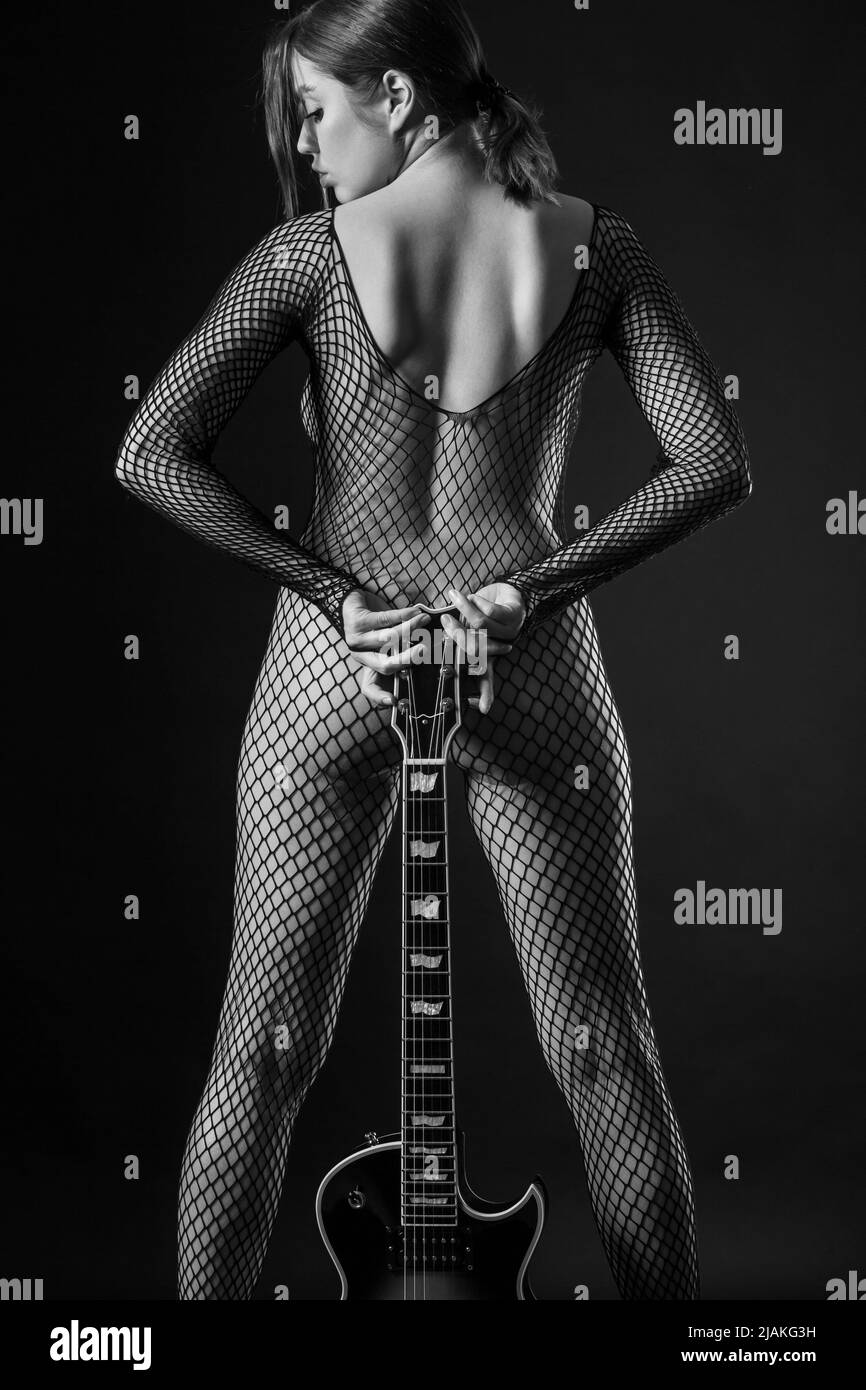 Sexy Frau in Netzbody Strumpf hält eine E-Gitarre. Stockfoto