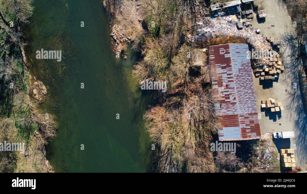 Drohnenfoto von Industriegebäuden Europaletten in der Nähe des Flusses und der Brücke Stockfoto