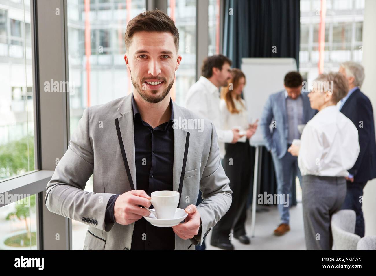 Junger Geschäftsmann im Gespräch auf dem Smartphone während einer Kaffeepause im Büro Stockfoto