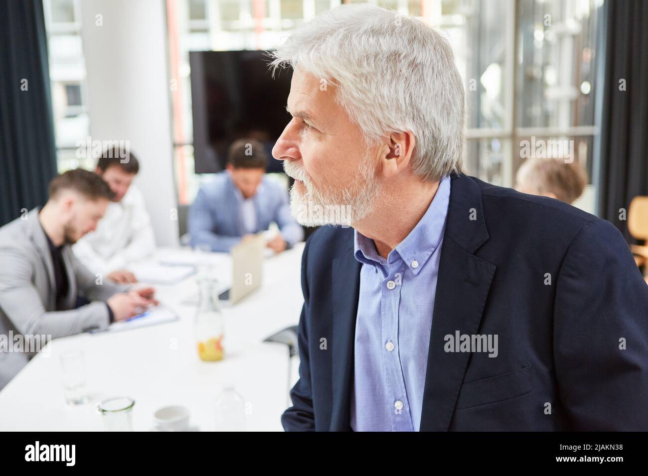 Geschäftsmann als Unternehmer oder Berater mit Team im Hintergrund am Konferenztisch Stockfoto