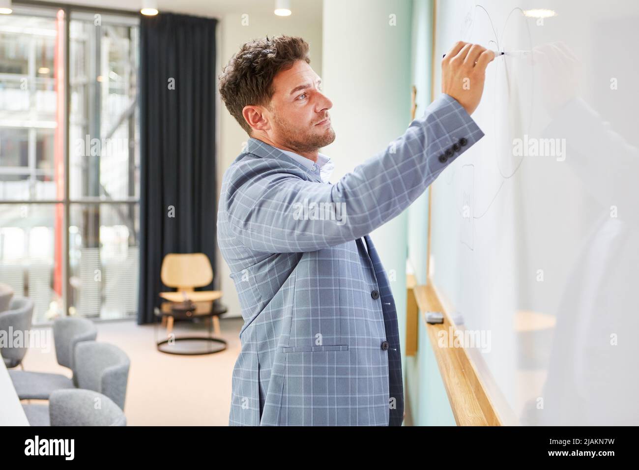 Während einer Präsentation schreibt ein Unternehmensberater oder Hochschullehrer auf das Whiteboard Stockfoto