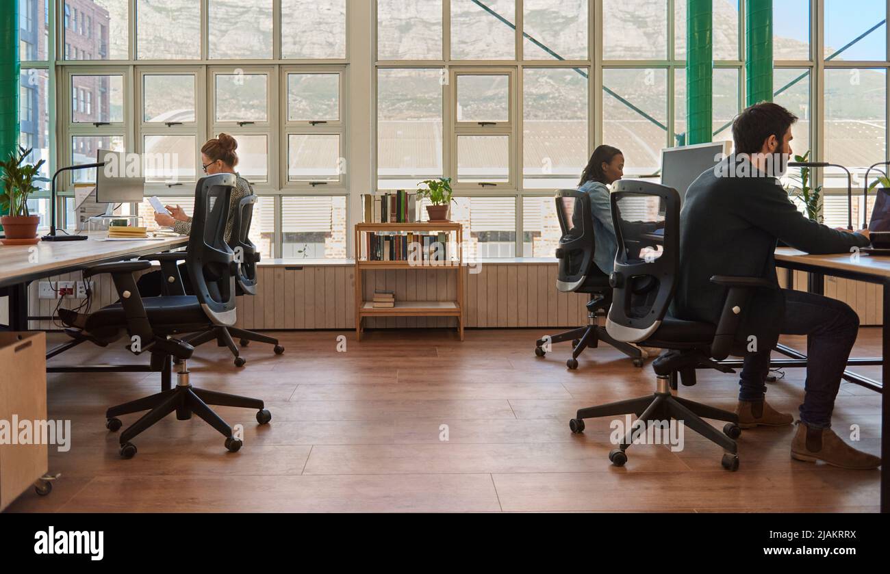 Eine vielfältige Gruppe junger Geschäftsleute, die an ihrem Schreibtisch in einem Büro arbeiten Stockfoto