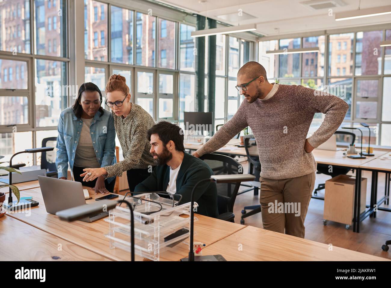 Eine Gruppe von konzentrierten Geschäftsleuten, die an einem Laptop zusammenarbeiten Stockfoto
