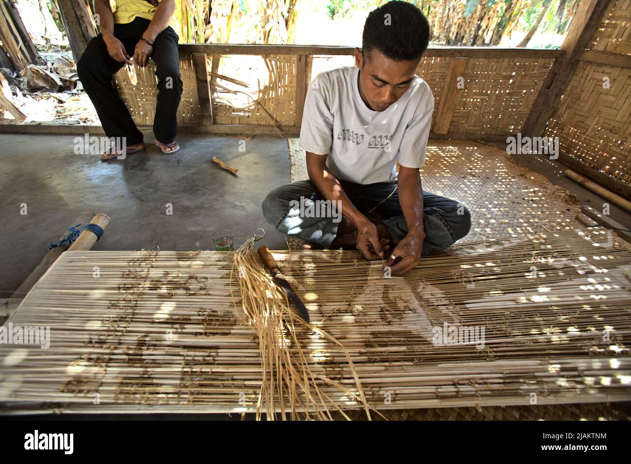 Ein Mann, der in der Werkstatt von Ama Nay Tukang, einem berühmten Händler, in Waingapu, East Sumba, East Nusa Tenggara, mit Mustern für traditionelle sumbanesische Gewebe arbeitet, Indonesien. Stockfoto