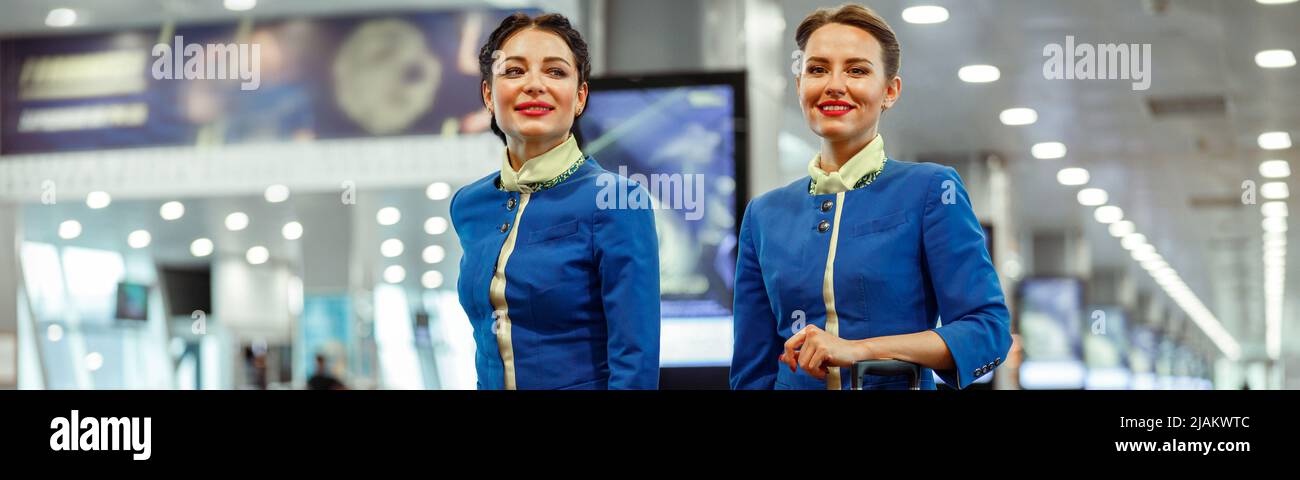 Fröhliche Frauen Stewardessen, die am Flughafenterminal entlang laufen Stockfoto