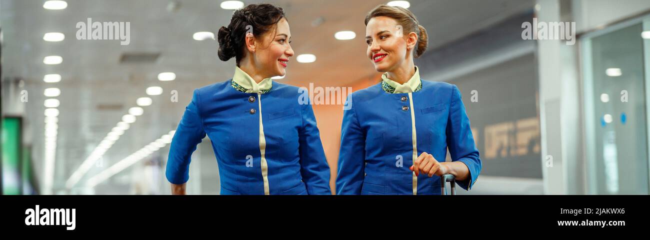 Fröhliche Stewardess mit Reisetaschen, die im Flughafenterminal stehen Stockfoto