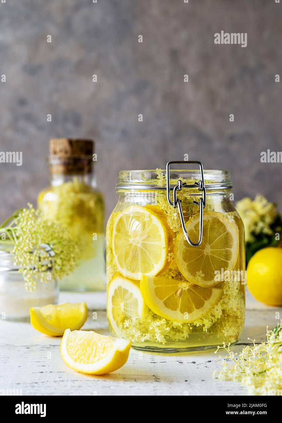 Holunderbeerenwasser oder Sirup aus frischen Blumen und Zitronen als Grundzutaten. Grauer Hintergrund Stockfoto