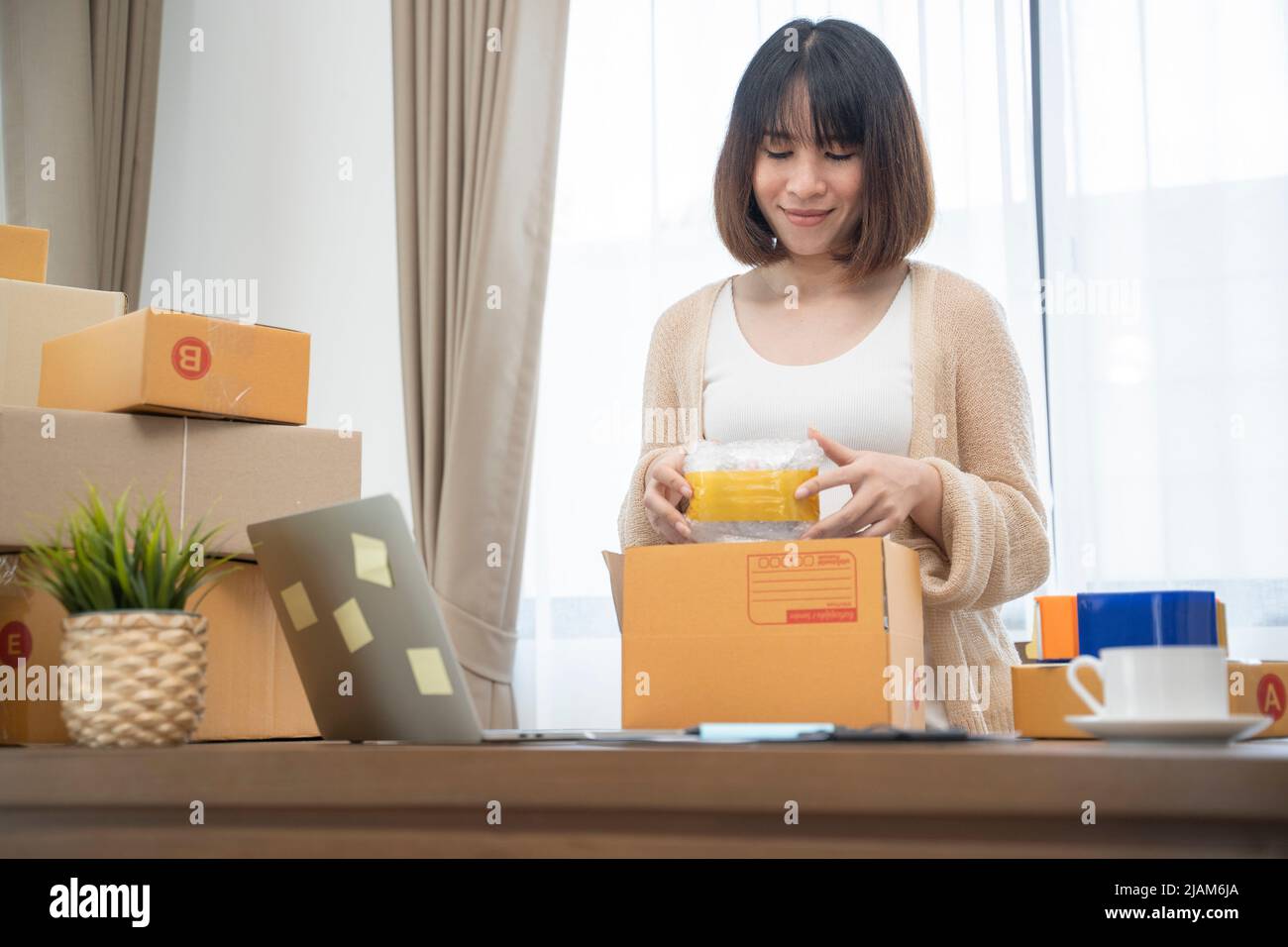 Asiatische Frau, die in Boxen verpackt, um zu Hause zu arbeiten Small Business Owner oder Startup Small Business Entrepreneurs, die an Online-Marketing-Versandkartons arbeiten. Stockfoto