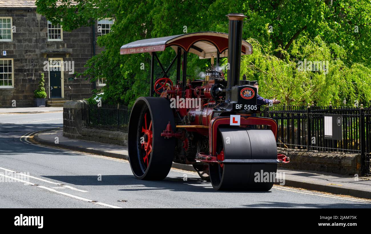 Rot-schwarzes, stationäres, schweres Dampffahrzeug, das am Straßenrand geparkt ist (L-Schild und Kennzeichen vorne) - Burley-in-Wharfedale, West Yorkshire England, Großbritannien. Stockfoto