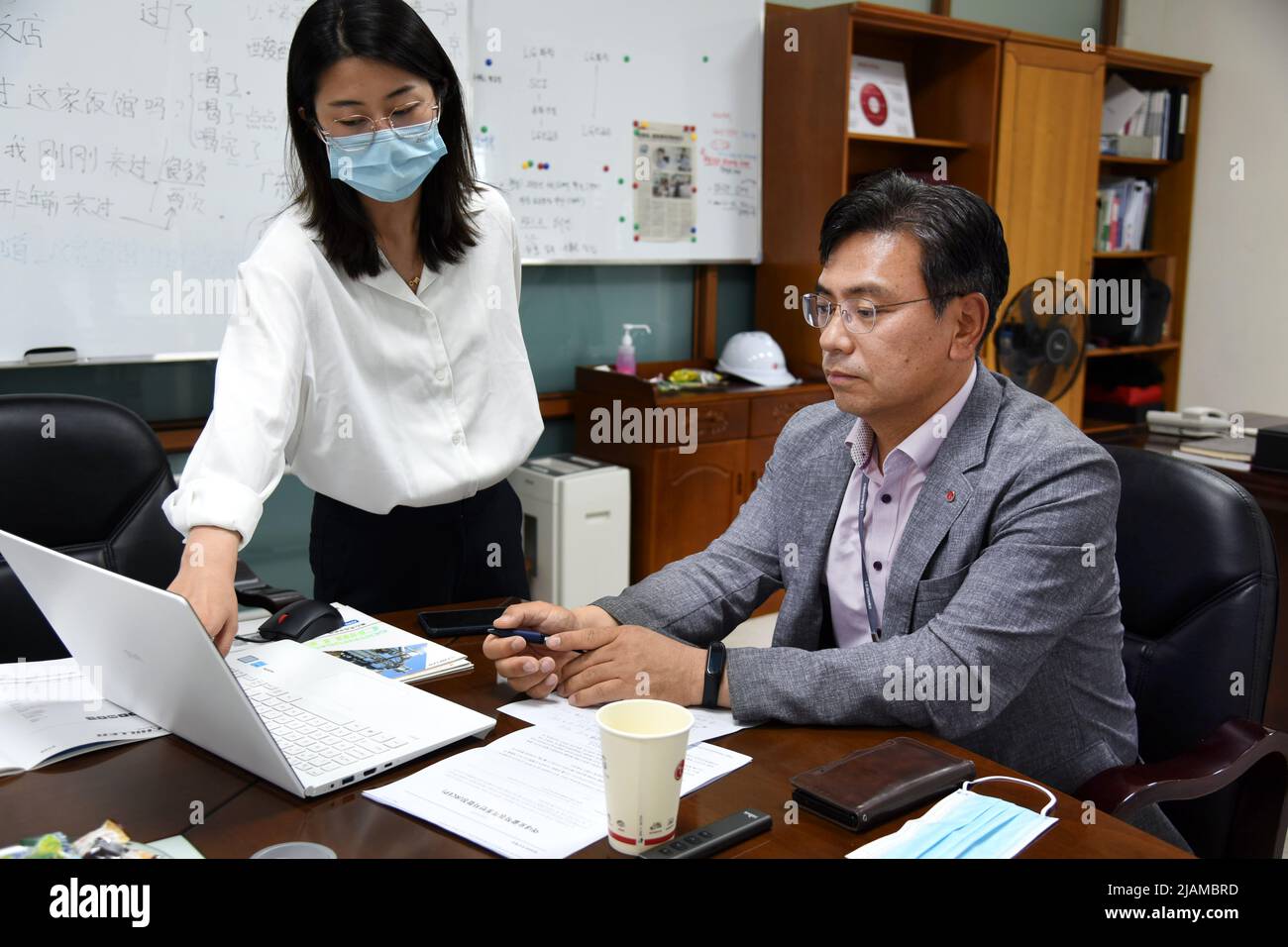 Jinan, Chinas Provinz Shandong. 26.. Mai 2022. Sang Chul Nam (R), Präsident von LG Electronics Air-Conditioning (Shandong) Co., Ltd., hört sich den Bericht eines Mitarbeiters in Qingdao, der ostchinesischen Provinz Shandong, am 26. Mai 2022 an. Quelle: Li Ziheng/Xinhua/Alamy Live News Stockfoto