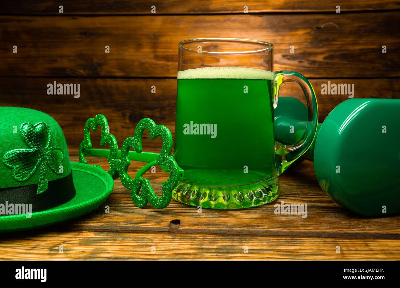 Schwere Hantel, Glas grünes Bier, irischer Hut mit Blattklee, schamsteinförmige Gläser. Gesundes Fitness-Studio-Kompositionskonzept für den St. Patrick's Day Stockfoto