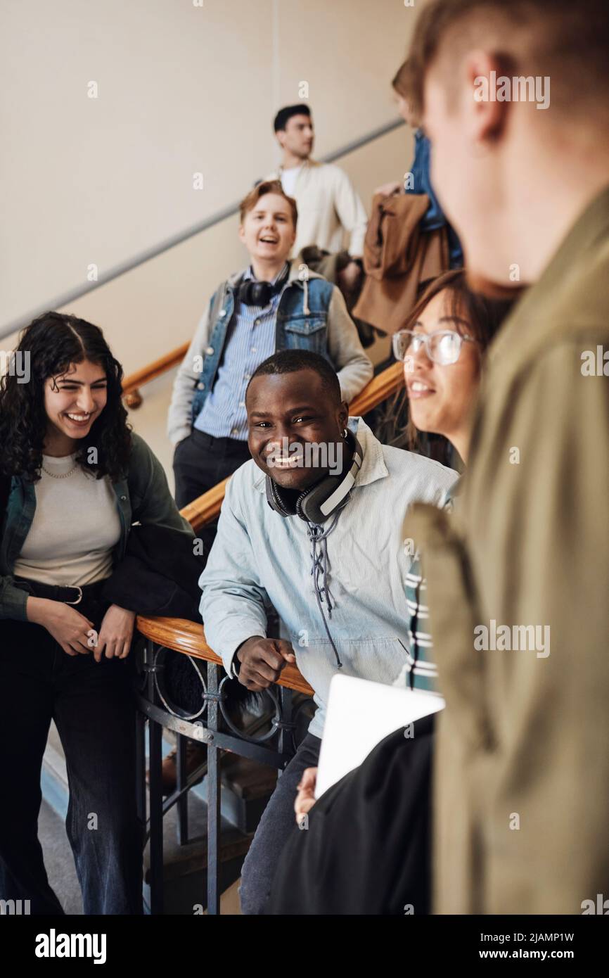 Glückliche junge, multirassische Studenten genießen im Treppenhaus der Universität Stockfoto