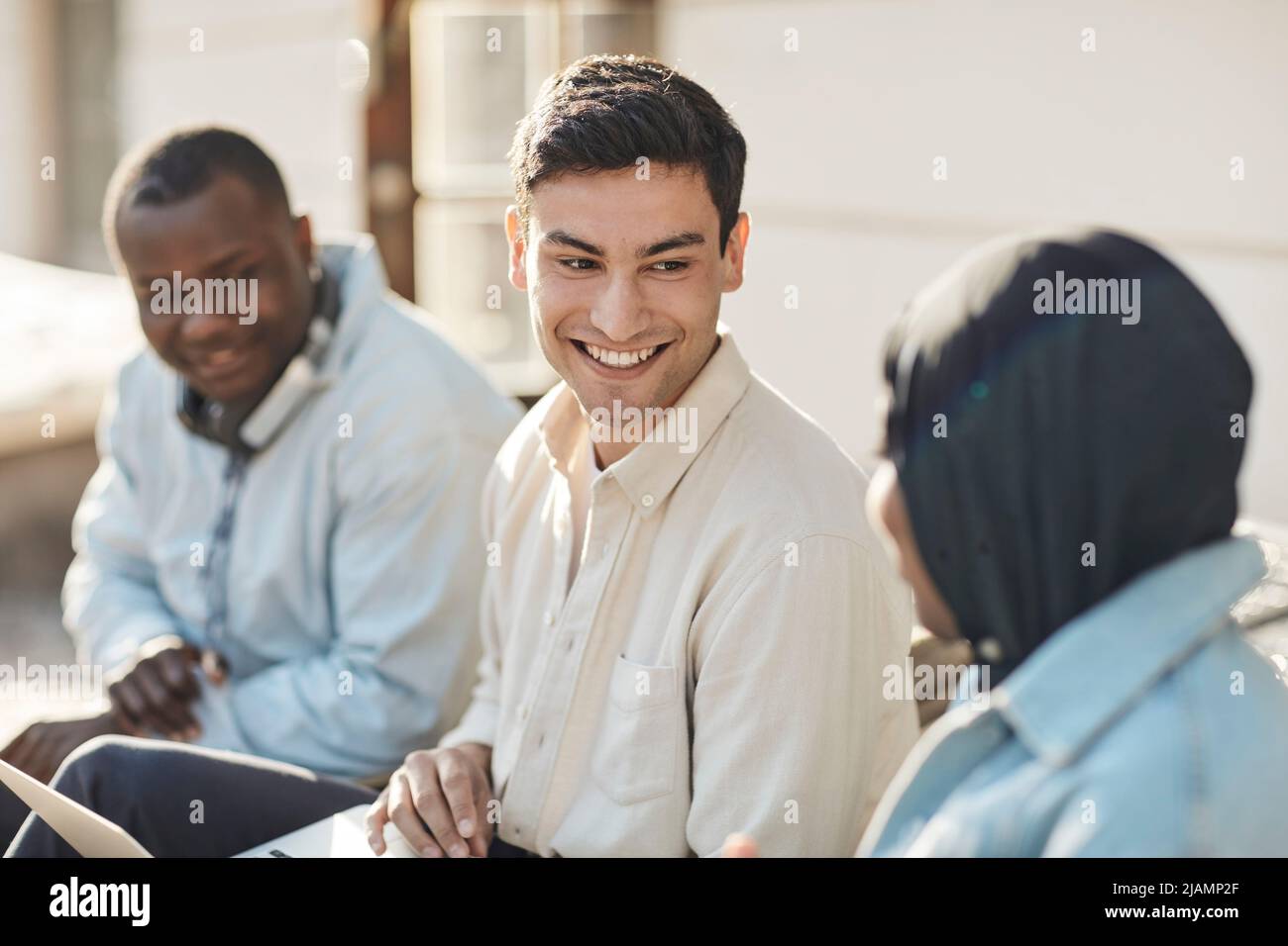 Glückliche männliche Studenten, die eine Freundin beim Gespräch auf dem Universitätscampus anguckend angeschaut haben Stockfoto