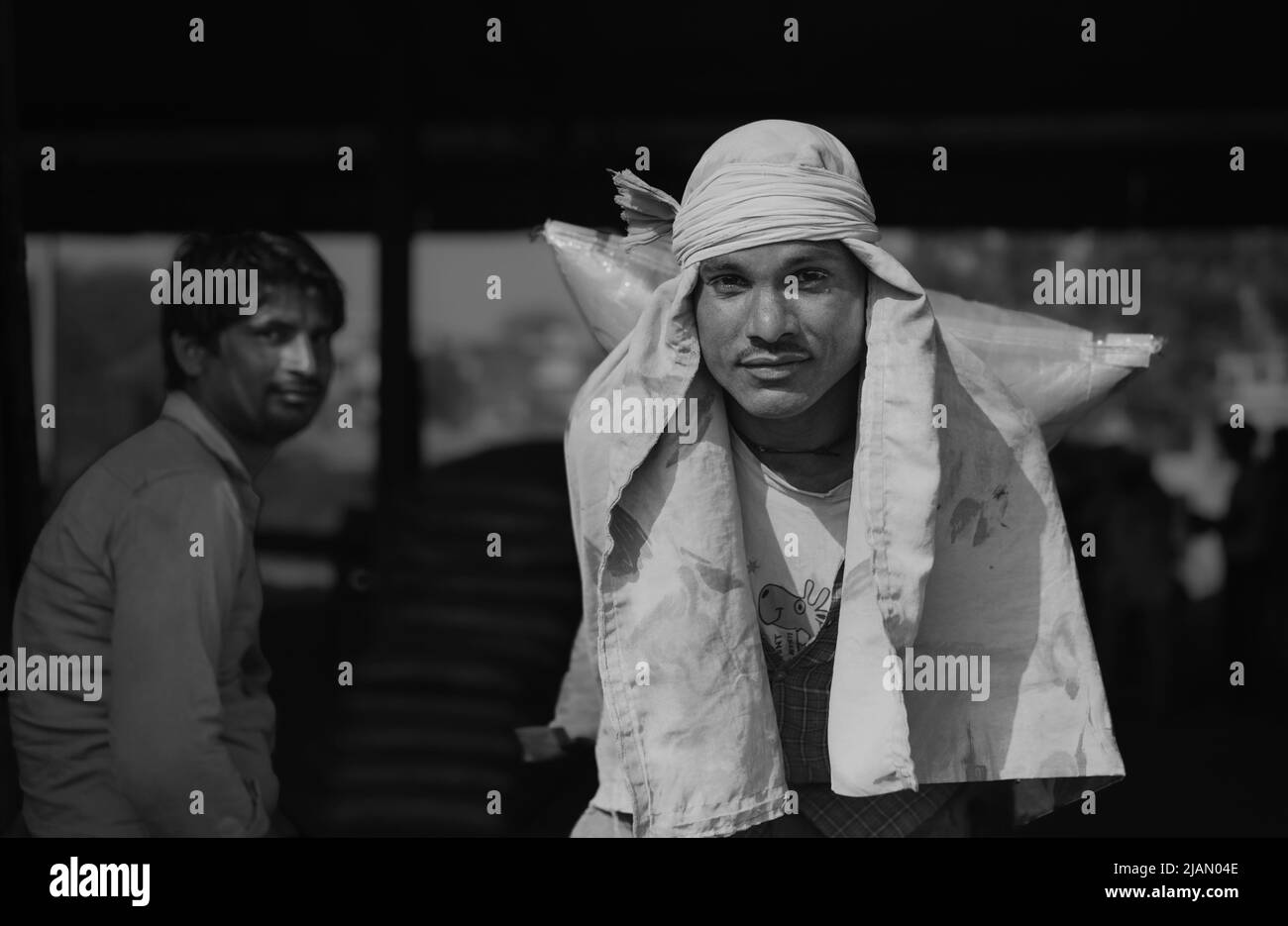 Ehrliches Porträt eines Mannes, der in Mathura, Indien, schwere Zementsäcke vom Eisenbahnknotenpunkt zum wartenden Lastwagen bewegt. Stockfoto