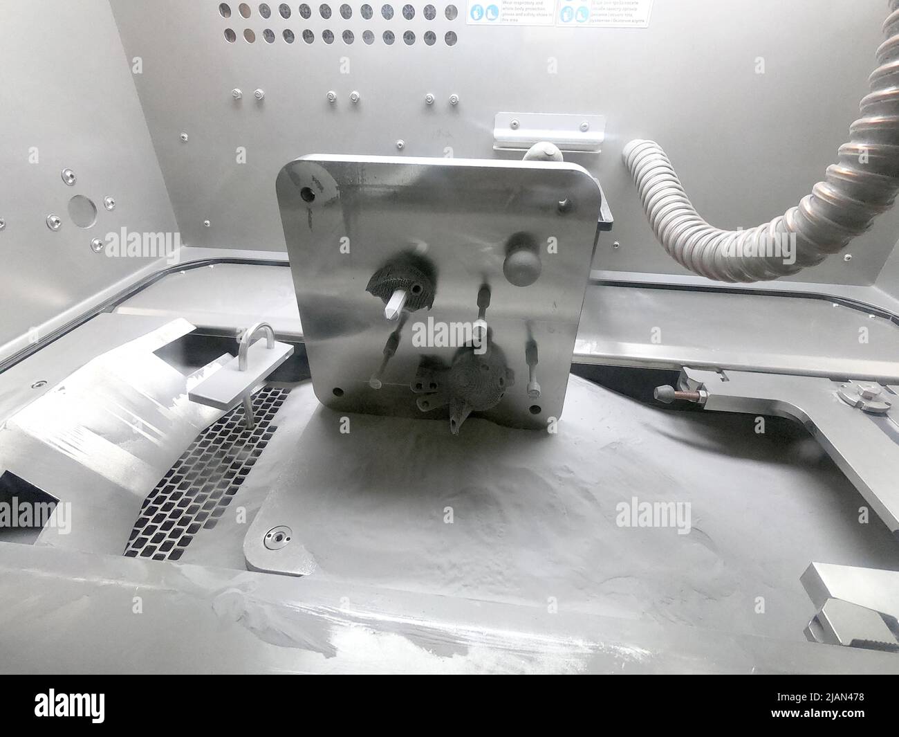 Plattform mit Objekten aus Metall gedruckt Pulverständer in der Arbeitskammer im Inneren 3D Drucker für Metall. Laser Sintermaschine für Metall im Inneren. Plattform mit bedruckten Objekten bedeckt Metallpulver. Stockfoto