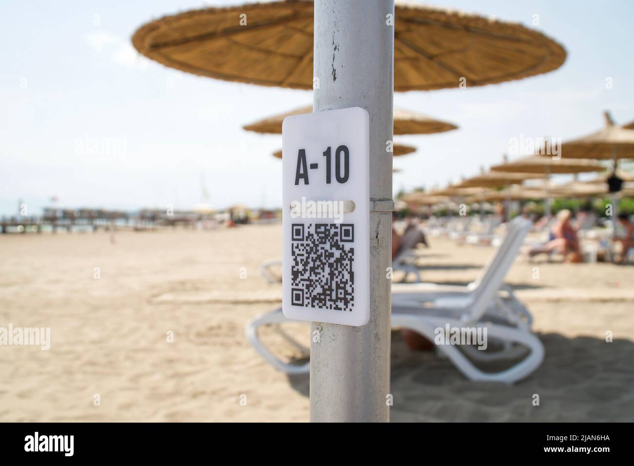 QR-Code auf der Stange am verschwommenen Strand. QR-Code mit Sitzplatznummer A10 für Auswahlmenü Stockfoto