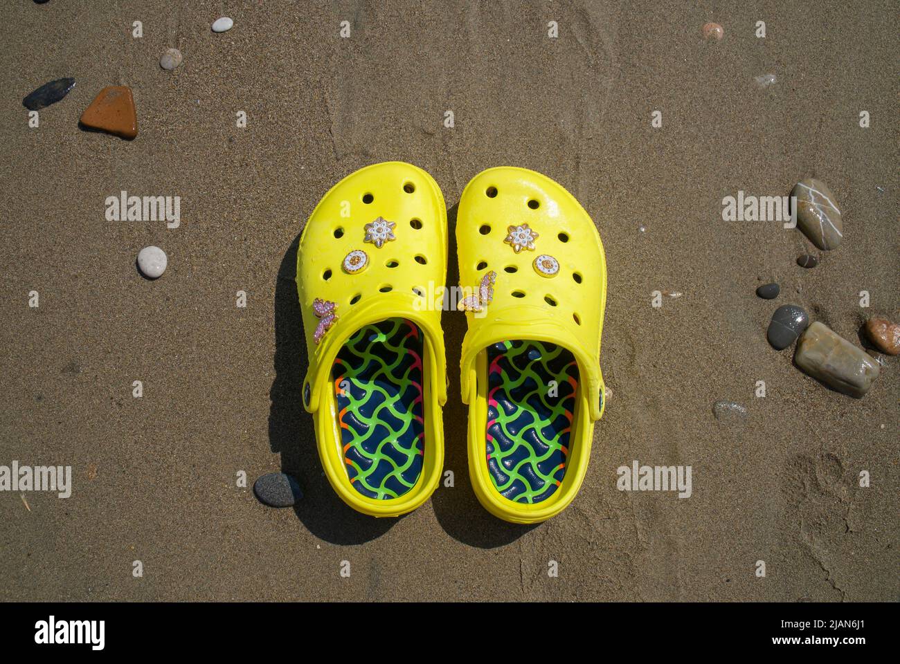 Gelbe Flip Flops am Strand. Gelbe Sandalen, Sommerurlaub trendige Schuhe, Schuhe Stockfoto