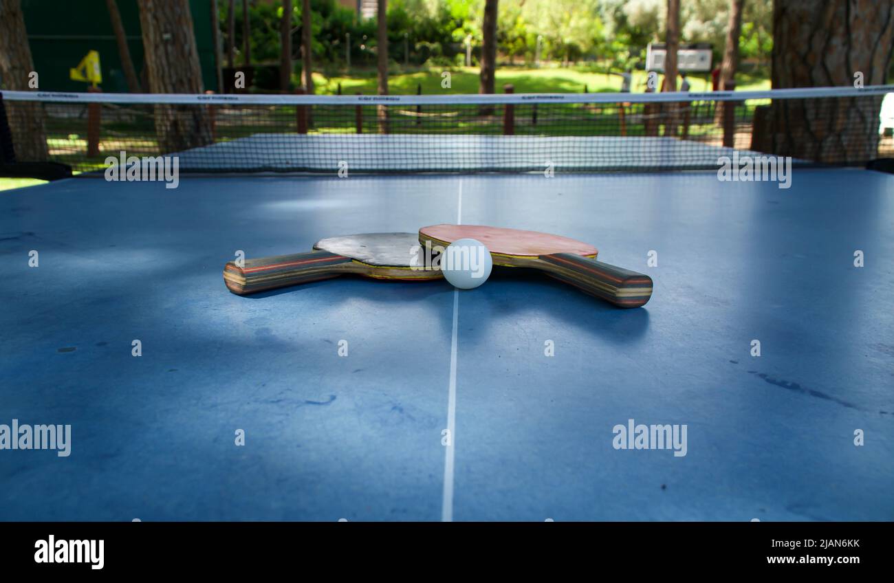 Schläger und Ball auf der blauen Tennistabelle im Freien. Konzept für sportliche Aktivitäten Stockfoto