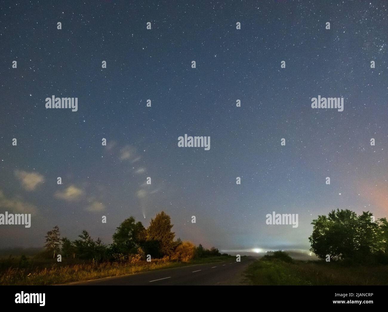 Komet Neowise C2020 F3, wie er im Sommerhimmel über einer Wiese in der Nähe der Landstraße, Region Lviv, Ukraine fliegt. Stockfoto