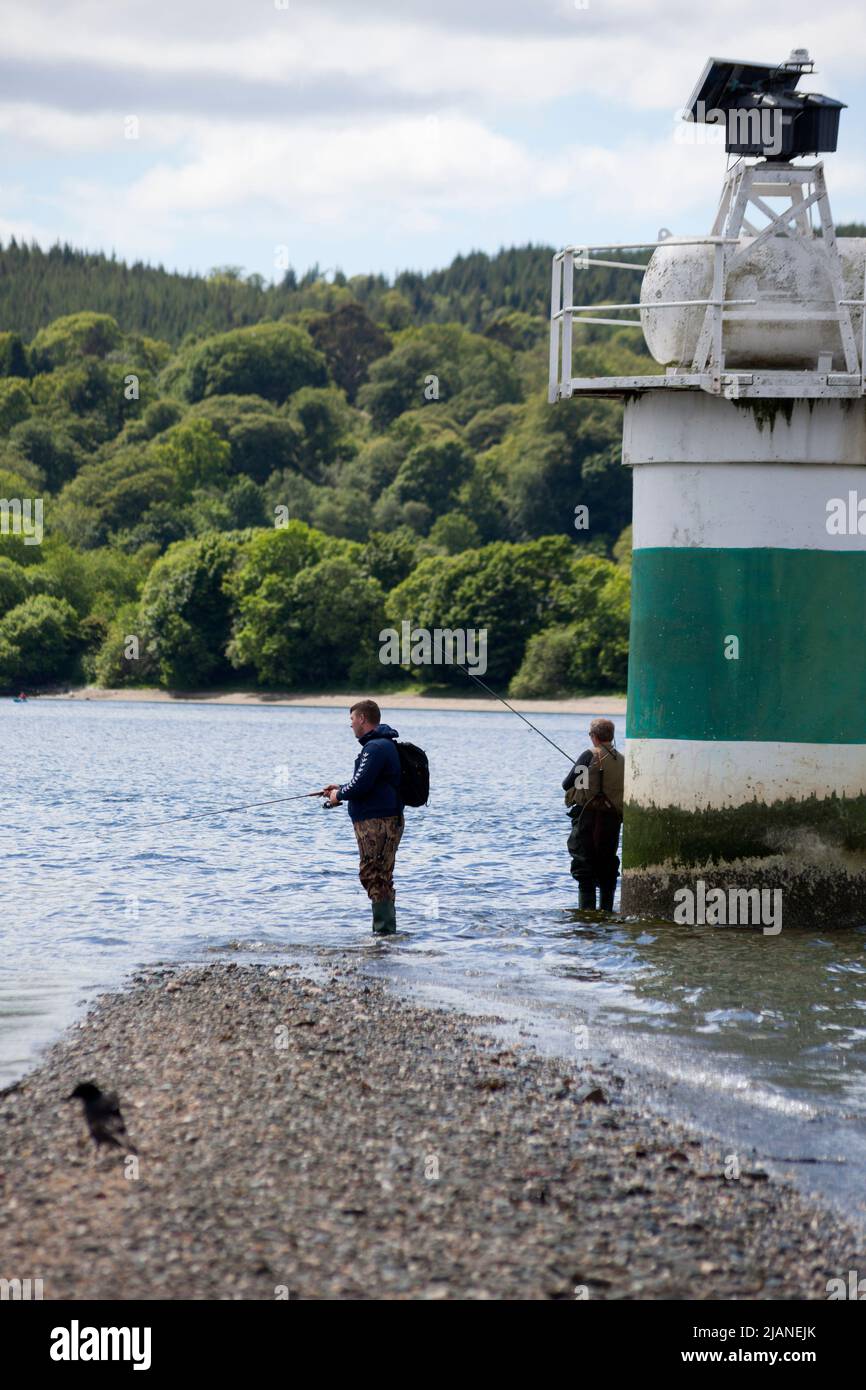 Angler fischen in Rhu Spit mit Navigationslicht in Rhu, Schottland Stockfoto