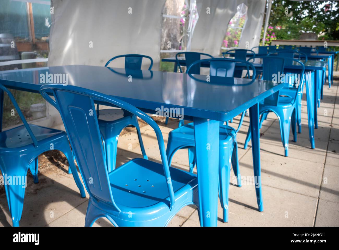 Farbenfrohe Aussicht auf leuchtend blaue Stühle, die sich um einen blauen Tisch auf der Außenterrasse eines Restaurants versammeln Stockfoto