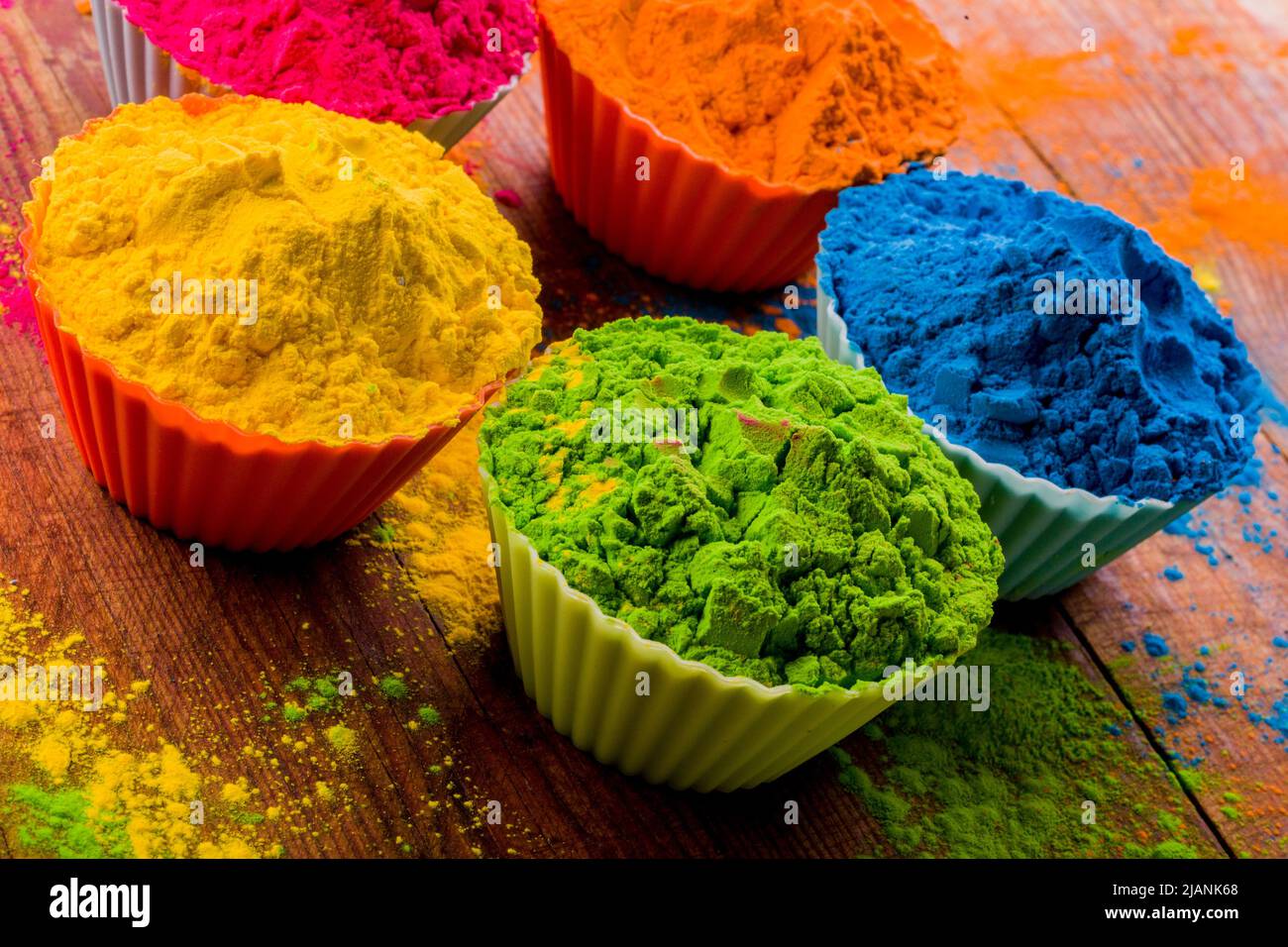 Buntes Holi Pulver in Tassen Nahaufnahme. Leuchtende Farben für das indische holi-Festival in Tontöpfen. Selektiver Fokus. Schwarzer Hintergrund, Draufsicht Stockfoto