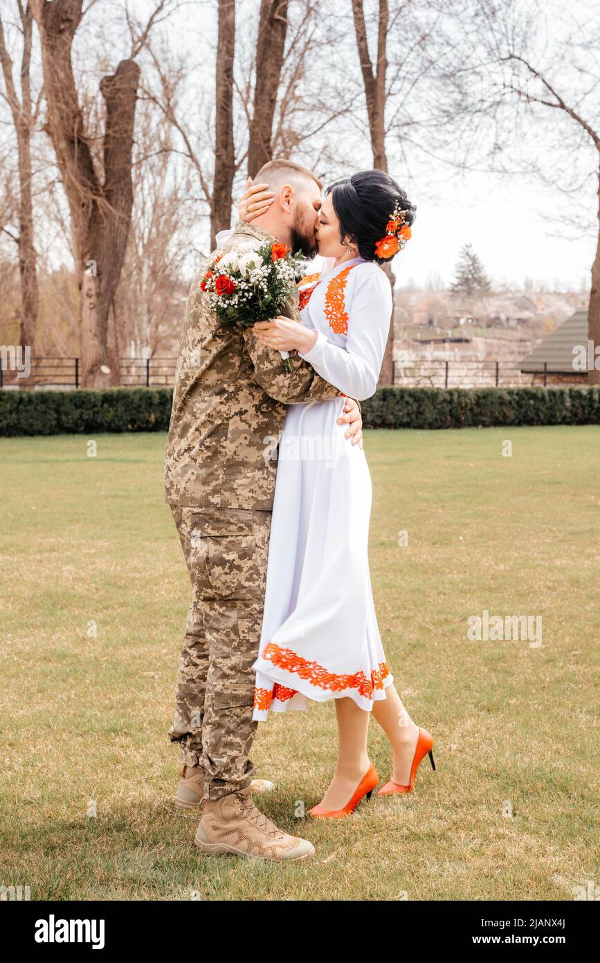 der ukrainische Bräutigam in der Militäruniform umarmt und küsst die Braut. Hochwertige Fotos Stockfoto