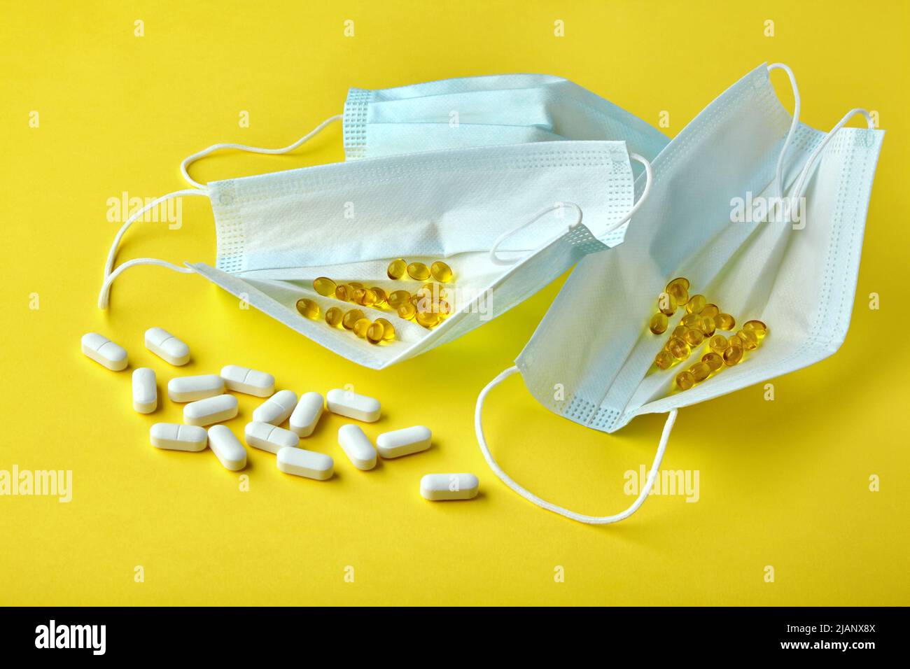 Medizinische Masken und Pillen auf gelbem Hintergrund. Prävention und Behandlung von Virusinfektionen Stockfoto