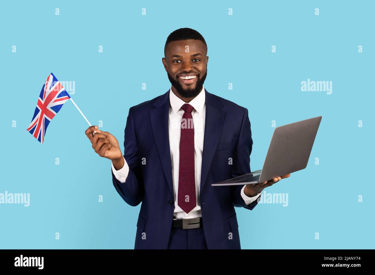 Schöner Schwarzer Geschäftsmann In Anzug Holding Laptop Und Britische Flagge Stockfoto