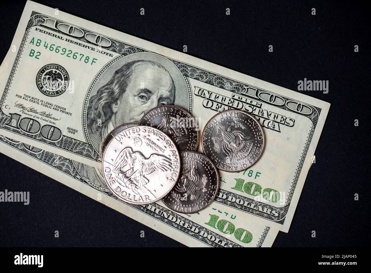 Dollar-Münzen auf US-Dollar-Banknoten. Schwarzer Hintergrund mit US-Währung Stockfoto