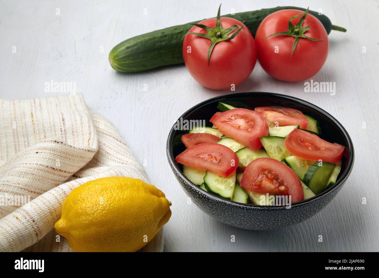 Sommerküche... Schüssel mit gehackten Tomaten und Gurken mit Zitrone gewürzt Stockfoto